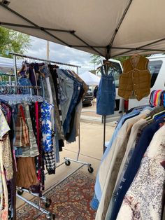 an outdoor market with clothes on display under a tent