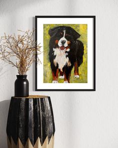 a painting of a black and white dog is hanging on the wall next to a vase