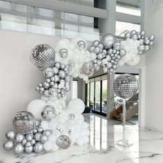 a room filled with lots of silver and white balloons