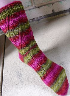 A toe-up sock with an asymmetrically placed openwork pattern of leaves, that winds up the foot and around the leg, ending in an eyelet rib at the top edge. Shown here in Twisted Fiber Arts Merino Sock, color TalonSuggested Yarns: Modern Deco Lace, Better Breakfast Fingering, Stone Soup Fingering, Kent Lace, Dragonfly Fibers Fingering Dance Rustic Silk Endive, or any sock yarn that knits to 8 sts per inch. A springy yarn with a higher twist is recommended to help sock keep its shape. Substituting Sock Yarn Knitting Patterns, Sock Knitting Pattern, Ohio City, Socks Knitting Pattern, Wine Socks, Baby Cocoon, Stitch Fit, Poppy Pattern, Sock Knitting Patterns