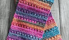 a multicolored crocheted neck tie laying on top of a wooden table