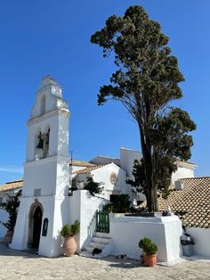 a white church with a bell tower and trees