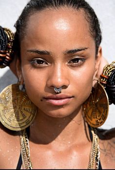 a close up of a person wearing large earrings and piercings on her nose,