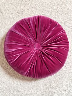 a purple round cushion sitting on top of a white carpet