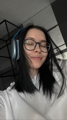 a woman with glasses and headphones on taking a selfie