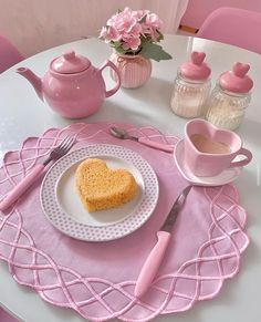 a heart shaped piece of cake on a white plate with pink napkins and cups