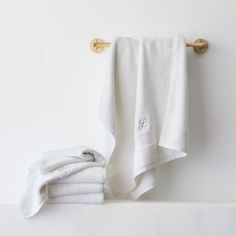 white towels are hanging on the wall next to a towel rack with gold handles and hooks