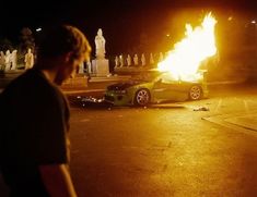 a person standing in front of a car on fire