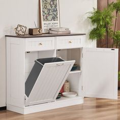 a white cabinet with an open door on the top and bottom, in front of a potted plant