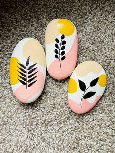 three painted rocks sitting on top of a carpet