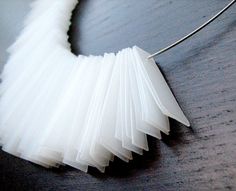 a necklace made out of white paper on a table