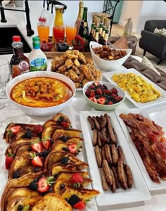 a table full of food and drinks on it, including breads, sausages, fruit, and other foods