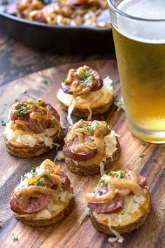 small appetizers are sitting on a wooden table next to a glass of beer