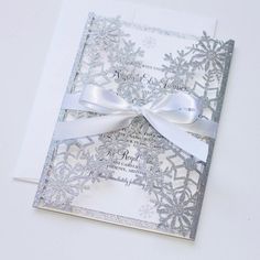 a white and silver wedding card with snowflakes on the front, bow at the back