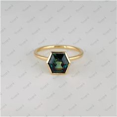 a gold ring with an octagonal cut green tourmaline stone in the center, on a white background