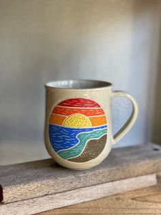 a coffee cup sitting on top of a wooden table next to a window sill