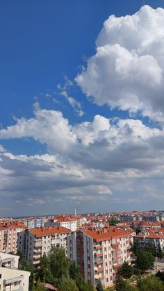 the sky is filled with clouds over some tall buildings and trees in front of them