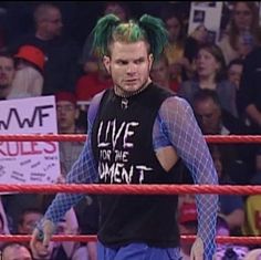 a man with green hair standing next to a wrestling ring