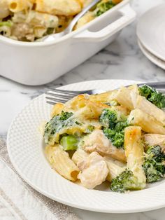 a white plate topped with pasta covered in chicken and broccoli next to a casserole dish