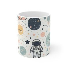 a white coffee mug with an astronaut print on the side and stars, planets, and sun