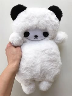 a hand holding a white stuffed panda bear