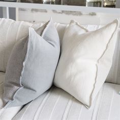 two gray and white pillows sitting on top of a bed