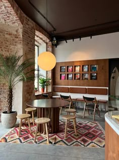 a dining room with chairs, tables and a rug on the floor in front of a brick wall