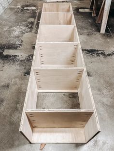 three wooden boxes sitting on top of each other in a room with concrete flooring