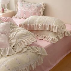 a pink bed with ruffled sheets and pillows