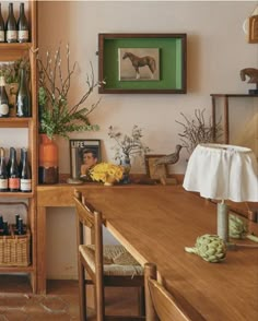 a wooden table topped with lots of bottles and vases next to a bookshelf