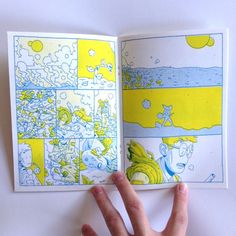 a hand is holding an open book with drawings on it and the pages are yellow