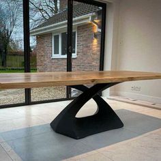 a wooden table sitting on top of a white tile floor next to a glass wall