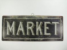 an old metal market sign hanging on a wall with the word market painted on it