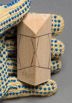 a wooden block sitting on top of blue and yellow knitted gloves