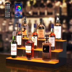 several bottles of alcohol are on a shelf with a cell phone and remote control in the background