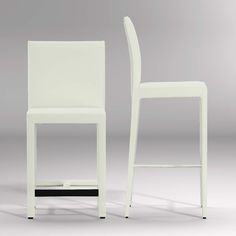 two white chairs sitting next to each other on a gray surface with one chair facing the camera