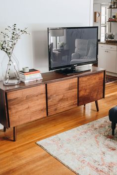 a flat screen tv sitting on top of a wooden entertainment center next to a couch