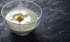 a glass bowl filled with yogurt on top of a black counter next to a spoon