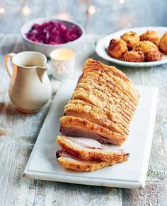 a white plate topped with sliced meat next to other plates filled with pastries and cranberries