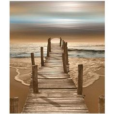 a wooden dock leading to the ocean on a sandy beach with waves coming in from the water