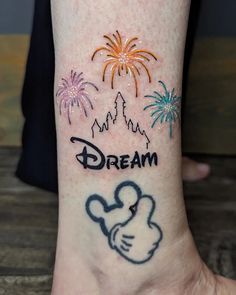 a person with a tattoo on their foot that says dream and fireworks in the sky