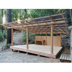 a wooden gazebo in the middle of a wooded area