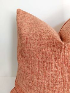 an orange pillow sitting on top of a white wall