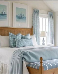 a bedroom with blue and white bedding, pillows and pictures on the wall above it