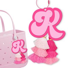 a pink purse with tassels hanging from it's side and an ornament shaped like the letter k