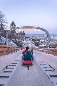 a person sitting on a sled in the middle of a snow covered park area