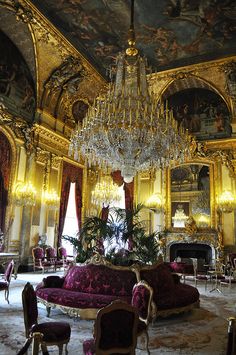 an ornately decorated room with chandelier and couches