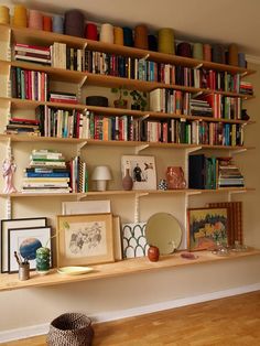 a bookshelf filled with lots of books on top of a hard wood floor