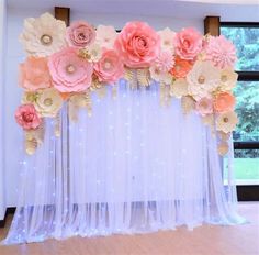 the backdrop is decorated with pink and peach paper flowers on sheer drapes, along with fairy lights