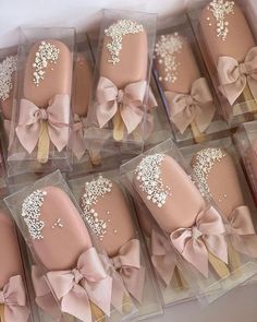 there are many pink and gold decorated cookies in the box with bows on them,